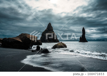 Moody Reynisdragar natural rock formation on Reynisfjara black sand beach in Atlantic ocean at Iceland 108471653