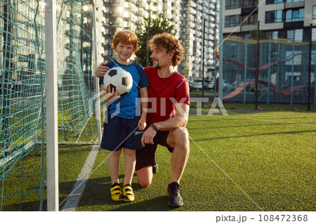 Happy father and little son standing near football gate 108472368
