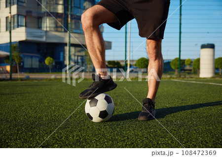 Man holding foot on soccer ball standing over football field 108472369