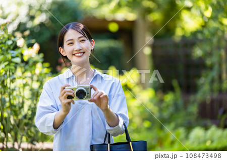 新緑の公園でカメラを持って撮影する女性 108473498