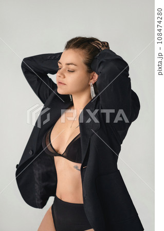 Portrait of a beautiful young woman with closed eyes in black lingerie sensually combing her hair into a bun 108474280
