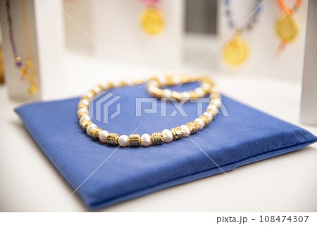 Pearl and gold bead necklace on a blue cloth 108474307