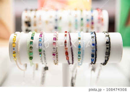 Colorful gemstone bracelets on a white stand with a blurred background 108474308