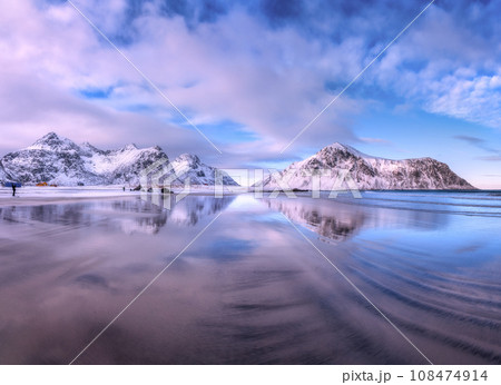 Sandy beach with blue sea reflected in water and rocks in snow 108474914