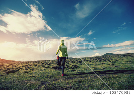 Woman trail runner cross country running at high altitude mountain peak 108476985