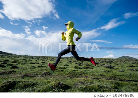 Woman trail runner cross country running at high altitude mountain peak 108476986