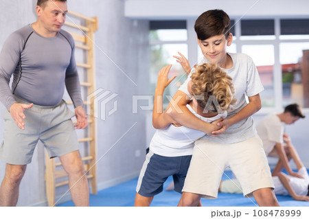 Diligent preteen student practicing self-defense techniques in pairs 108478999