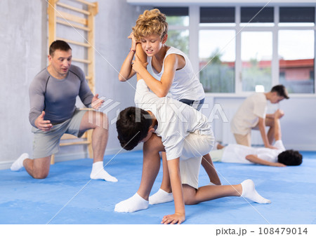 Two boys learn to do painful hand grip in self-defense lesson in sports gym 108479014