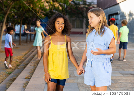 Two cheerful preteen girls enjoying walk along city street 108479082