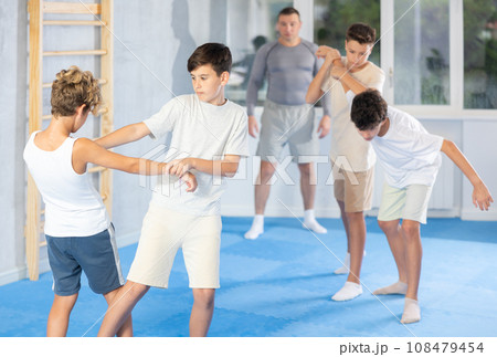 Sporty boys practices self-defence moves in pairs in sporty gym Sporty boys practices self-defence moves in pairs in sporty gym 108479454