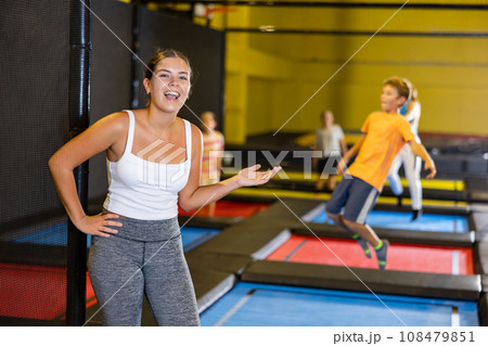 Teacher with children in trampoline center against background of children playing and jumping on trampoline 108479851