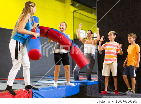 Preteen girl having fun on battle beam with other girl 108480095