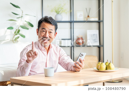 リビングでスマートフォンを操作するシニア男性。 108480790