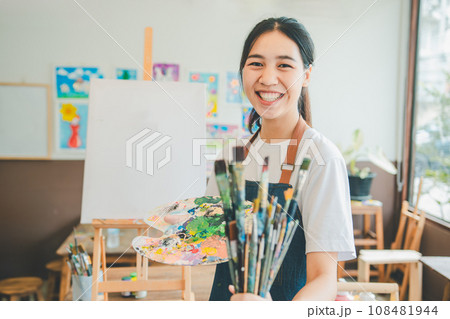 Portrait of Art student smiling happily while with watercolor painting on canvas doing some art projects on studio workshop Portrait of Art student smiling happily while with watercolor painting on canvas doing some art projects on studio workshop 108481944