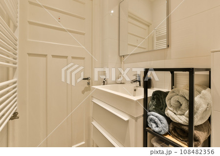 a bathroom with white walls and wood flooring, there is a towel rack on the wall next to the sink 108482356