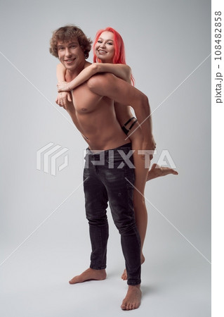 Happy topless woman trying to climb a muscled man's back Happy topless woman trying to climb a muscled man's back 108482858