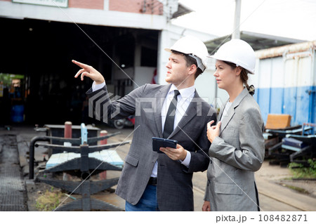 Young caucasian engineer man and woman in suit checking train with tablet in station. 108482871