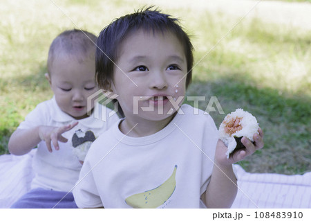 公園でほっぺたにお米粒をつけながらおにぎりを食べる男の子の兄弟 公園でほっぺたにお米粒をつけながらおにぎりを食べる男の子の兄弟 108483910