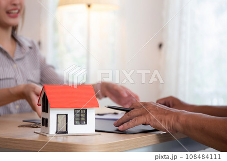 Closeup hands signing agreement document about buying home together at home. Closeup hands signing agreement document about buying home together at home. 108484111
