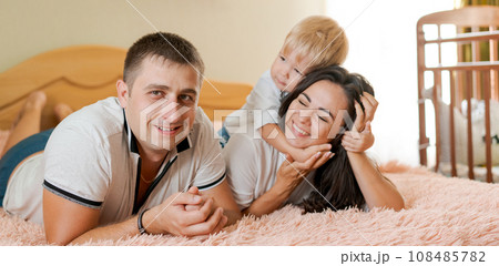 happy family lying on the bed and hugging, mom dad and little son happy family lying on the bed and hugging, mom dad and little son 108485782