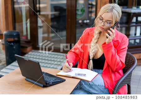 Beautiful woman sits at table in street cafe and works on tablet. Concept Beautiful woman sits at table in street cafe and works on tablet. Concept 108485983