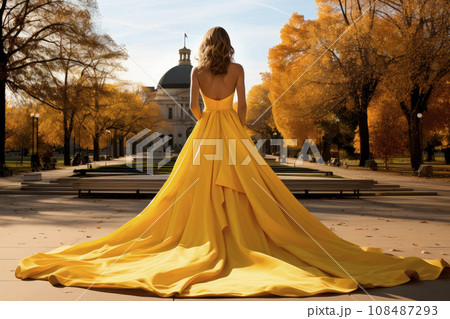 Rear view of beautiful woman wearing a very long yellow evening dress Rear view of beautiful woman wearing a very long yellow evening dress 108487293