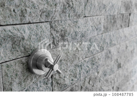 Shower faucet on stone wall in bathroom 108487785