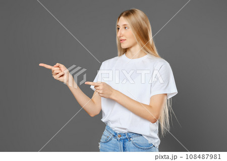 Young woman wearing jeans and shirt pointing to the side with both index fingers Young woman wearing jeans and shirt pointing to the side with both index fingers 108487981