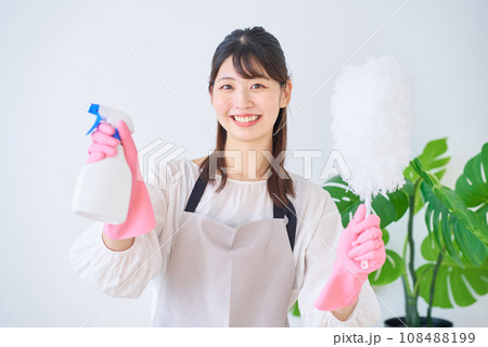掃除道具を持つ若いエプロン姿の女性 108488199