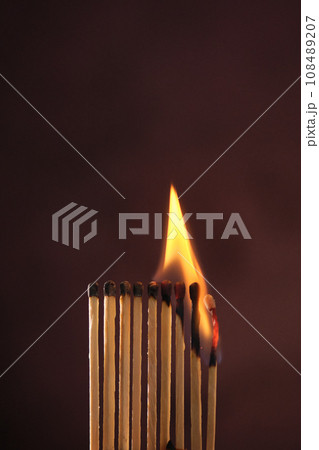 a row of matches are lit on a dark background 108489207
