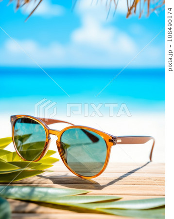 Closeup of black protective sunglasses on sandy beach at tropical seaside on warm sunny day. 108490174