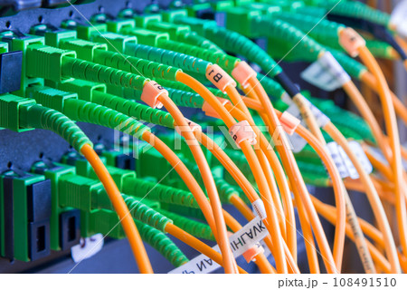 fiber optic cables plugged in network switch panel inside data center 108491510