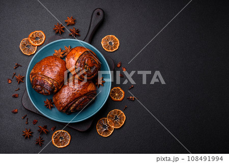 Delicious fresh sweet baked buns with poppy seeds and cinnamon on a ceramic plate 108491994