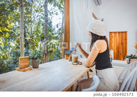 Traveler asian woman with Ice coffee plastic cup relax in cafe at Thailand 108492573
