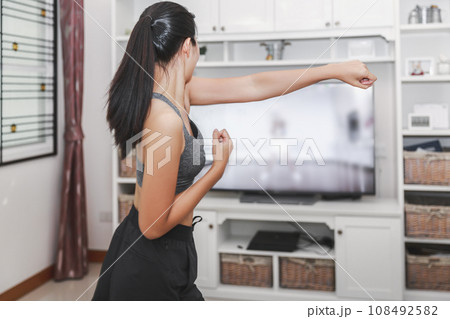 Fit asian woman training fitness exercise sport workout online class on tv from home Fit asian woman training fitness exercise sport workout online class on tv from home 108492582