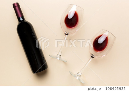 Glass of red wine and a bottle on colored table. Flat lay, top view wth copy space 108495925