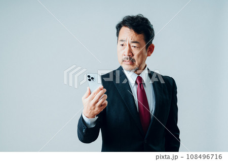 スマートフォンを操作するシニア男性。（グレーバック） 108496716