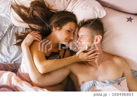 Top view of a smiling couple relaxing and lying in bed, looking at each other Top view of a smiling couple relaxing and lying in bed, looking at each other 108496803