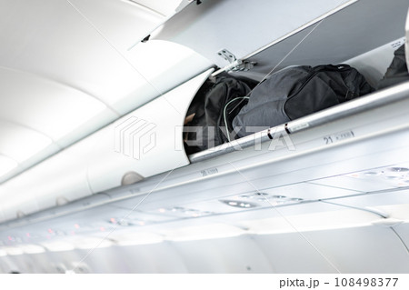 luggage on the top airplane shelf overhead passenger seat 108498377