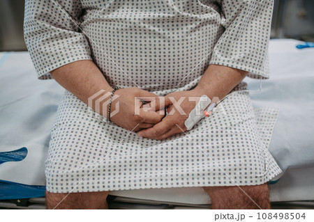 Close up of hands of overweight patient in hospital gown waiting for medical examination, test results in hospital, feeling anxious and scared. 108498504