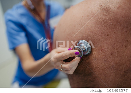Female doctor listening to bowel sounds of overweight patient using stethoscope. Obesity affecting middle-aged men's health. Concept of health risks of overwight and obesity. 108498577