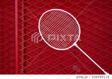 one badminton racket is hung on red grill by a cable tie for display in exhibition sports event 108499119