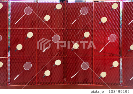 Table tennis and badminton rackets are hung on a red square grill steel grid, used as a backdrop for various events. 108499193