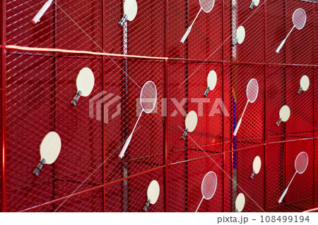 Table tennis and badminton rackets are hung on a red square grill steel grid, used as a backdrop for various events. Table tennis and badminton rackets are hung on a red square grill steel grid, used as a backdrop for various events. 108499194