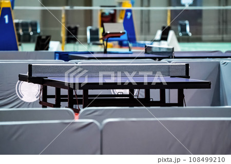 Blue table tennis or pingpong table is settle on a red, orange floor of the indoor court stadium for competitions tournament. 108499210