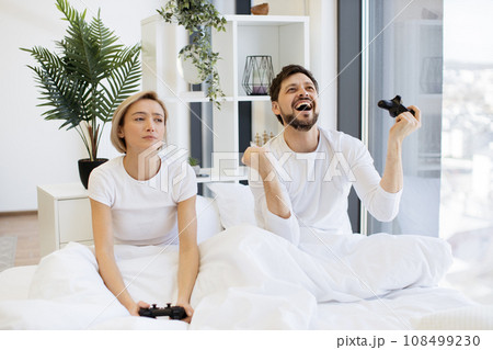 Caucasian couple in love have fun competing in laptop game using joysticks Caucasian couple in love have fun competing in laptop game using joysticks 108499230