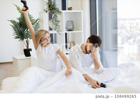 Caucasian couple in love have fun competing in laptop game using joysticks Caucasian couple in love have fun competing in laptop game using joysticks 108499265