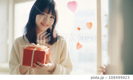 バレンタインのギフトを両手に持って微笑む可愛い女の子 108499823
