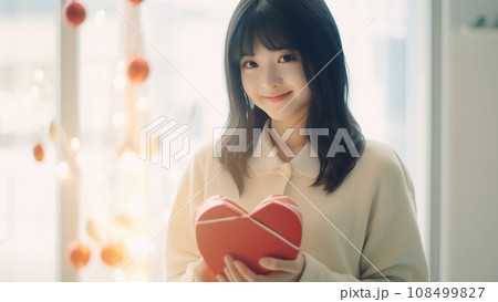 バレンタインのギフトを両手に持って微笑む可愛い女の子 108499827