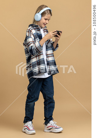 Teen in headphones with a smartphone in hands Teen in headphones with a smartphone in hands 108500496